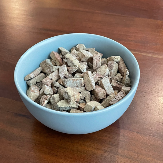 Blue bowl filled with free-dried liber pet treats on a wooden surface